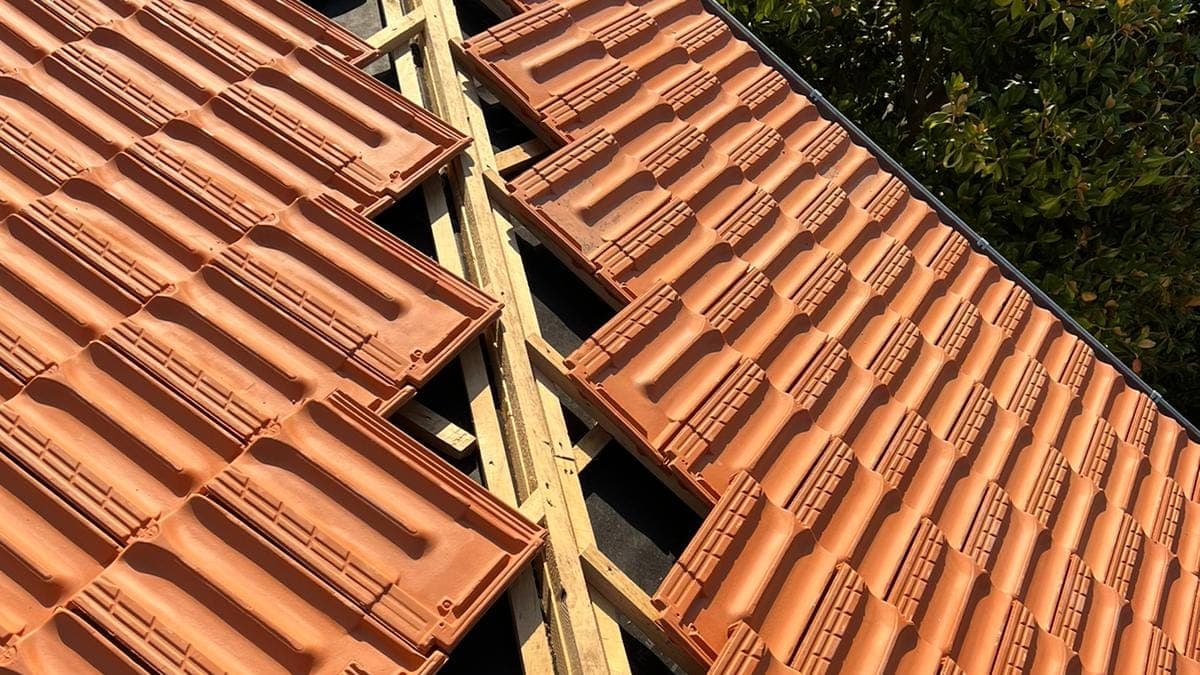 Tuiles mécaniques coupées le long d'un arêtier en cours de pose
