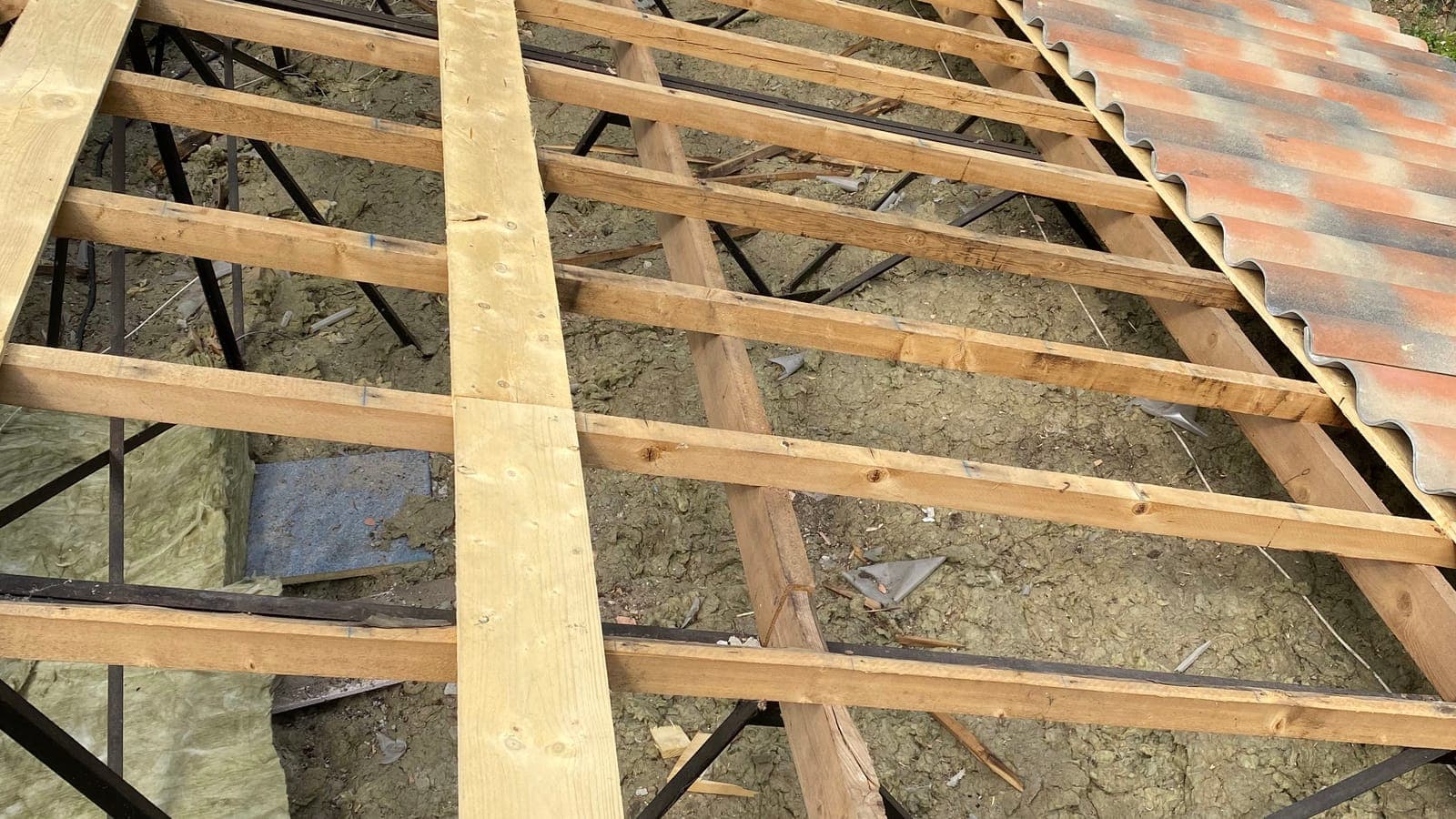 Chevrons et liteaux neufs sur un versant découvert, tuiles sur le pan voisin