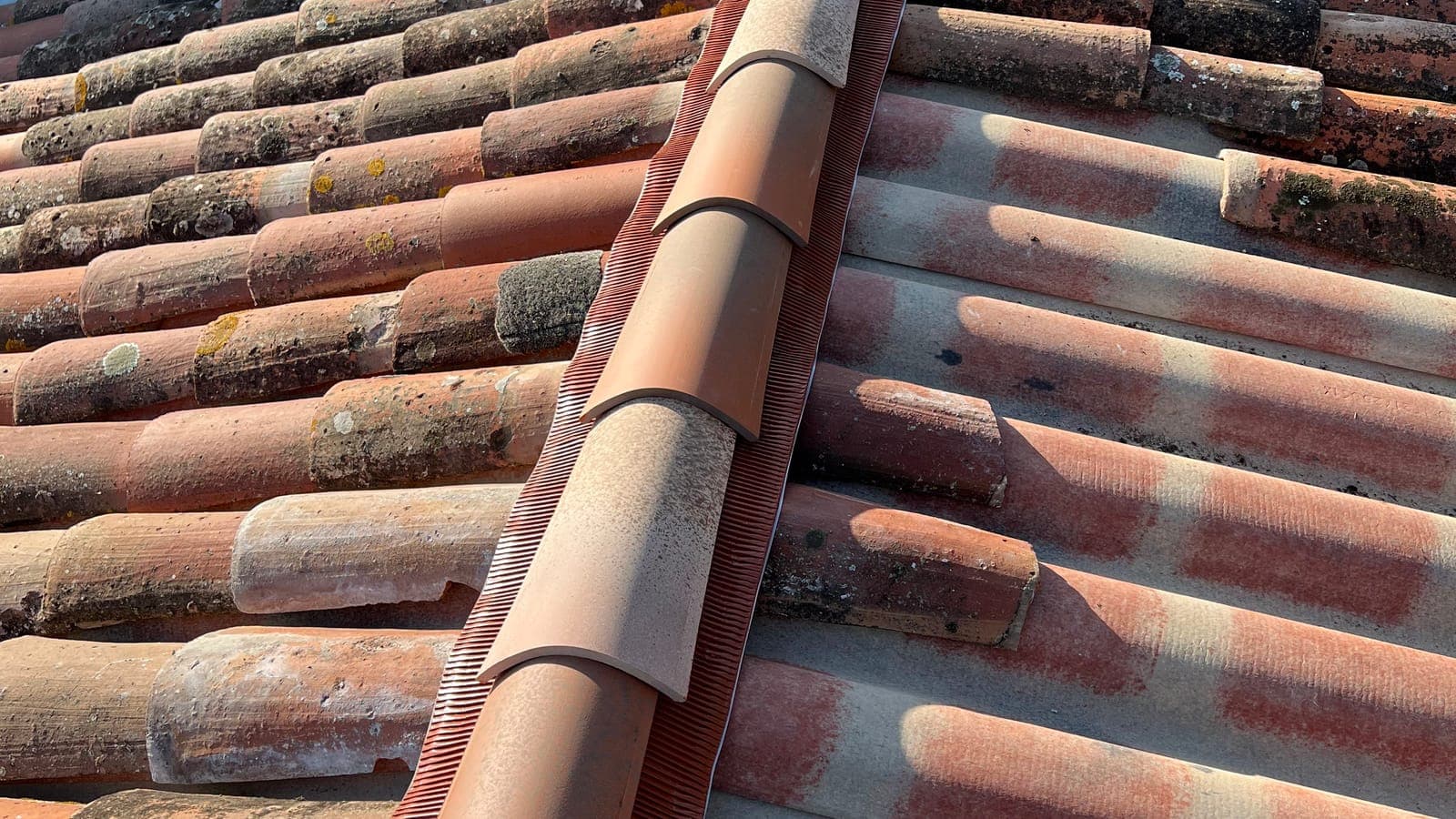 Tuiles faîtières posées sur un closoir ventilé entre deux pans de tuiles anciennes