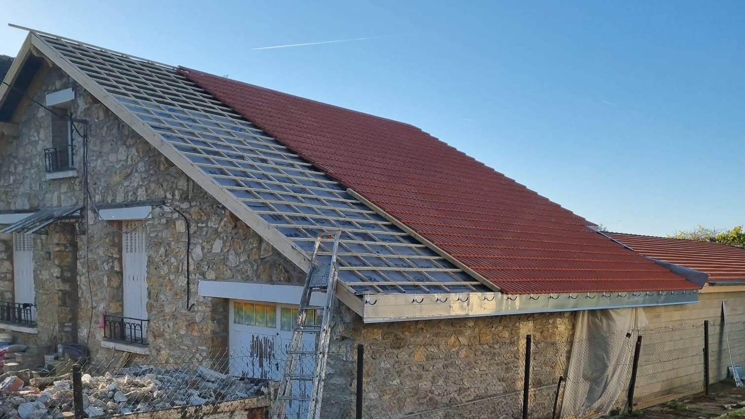 Maison en pierre en cours de réfection, un versant en tuiles neuves et l'autre sur liteaux