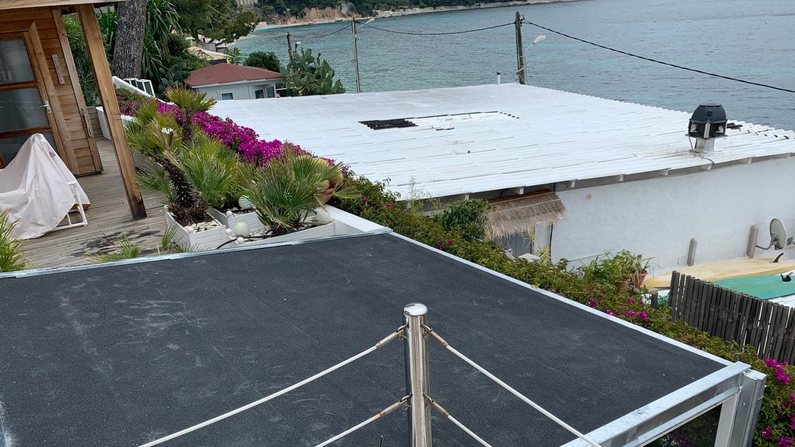 Toit-terrasse sous membrane d'étanchéité, garde-corps en inox, toits et mer en arrière-plan