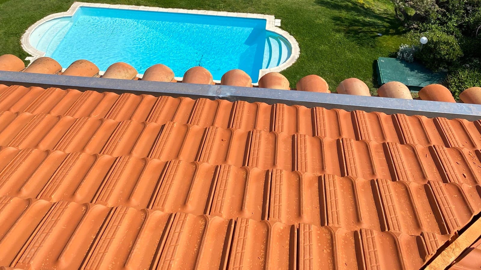 Pan de tuiles mécaniques en terre cuite et sa rive métallique, piscine en contrebas