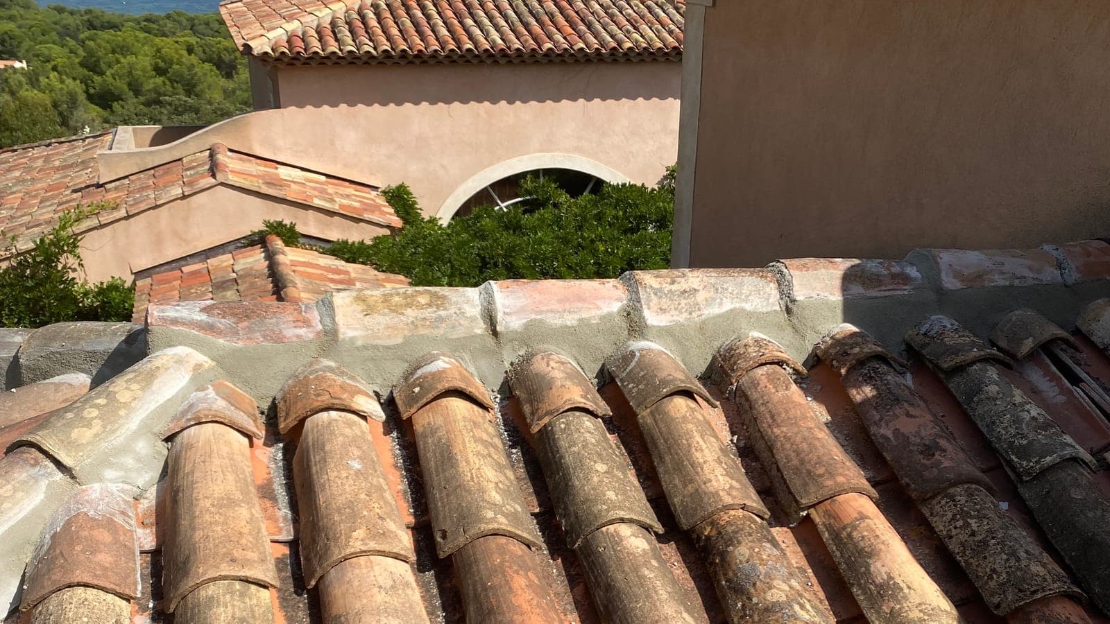Tuiles canal anciennes et faîtage au mortier devant une villa aux façades ocre